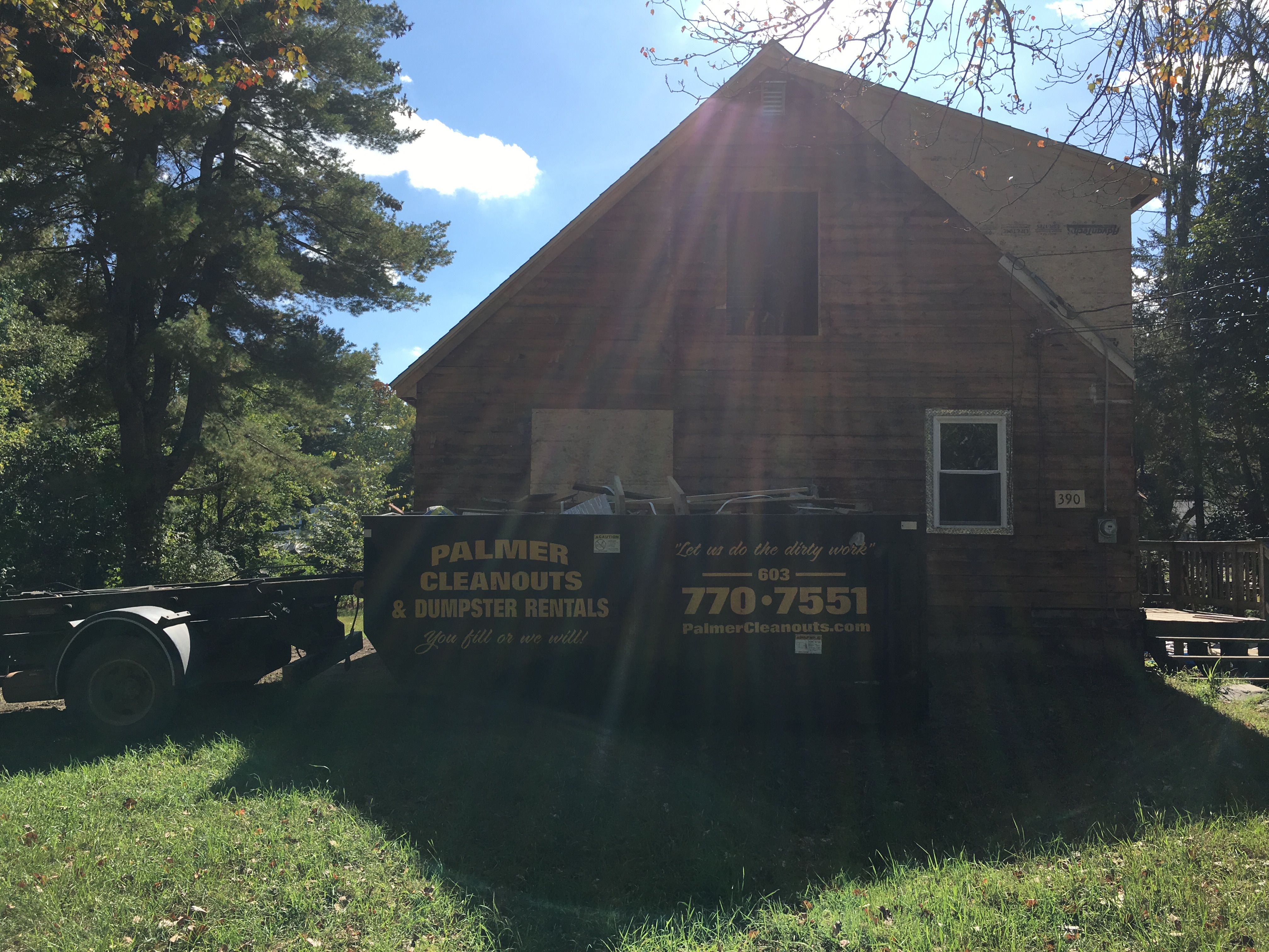 A dumpster from Palmer Cleanouts & Disposal, LLC parked in front of a house